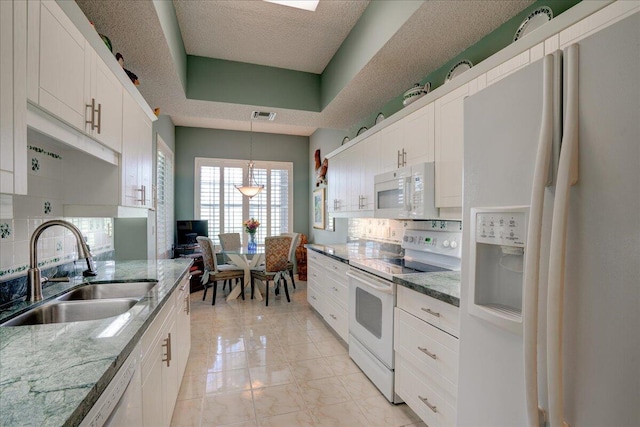 kitchen featuring white appliances, white cabinetry, sink, pendant lighting, and light stone counters