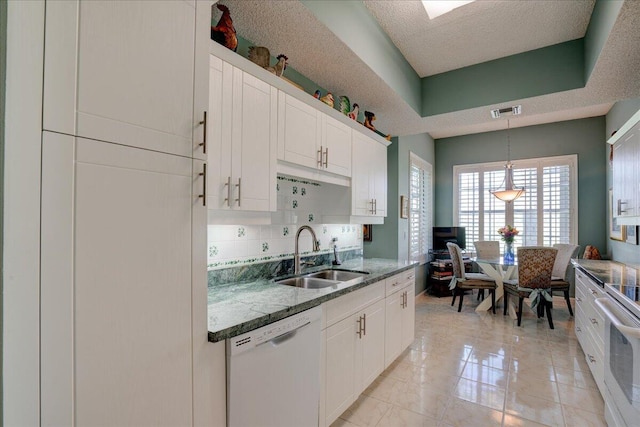 kitchen with white appliances, white cabinets, a textured ceiling, decorative light fixtures, and sink