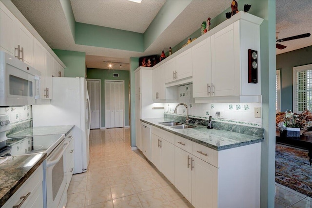 kitchen with white appliances, a textured ceiling, white cabinetry, sink, and backsplash