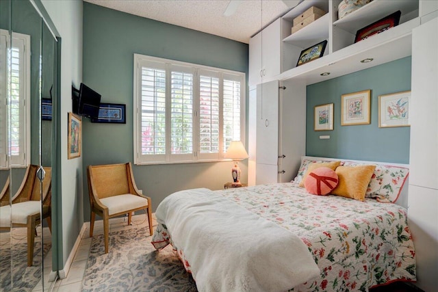 bedroom with ceiling fan, a textured ceiling, and light tile patterned flooring