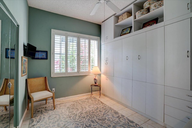 sitting room featuring ceiling fan, light tile patterned floors, and a textured ceiling