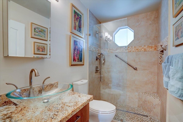 bathroom with a tile shower, toilet, and vanity