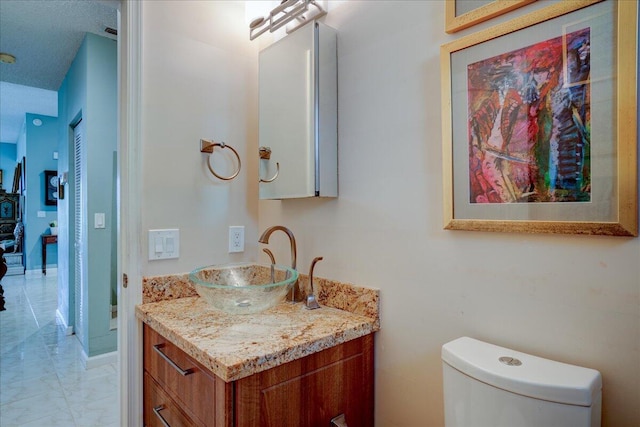 bathroom featuring vanity, toilet, and a textured ceiling