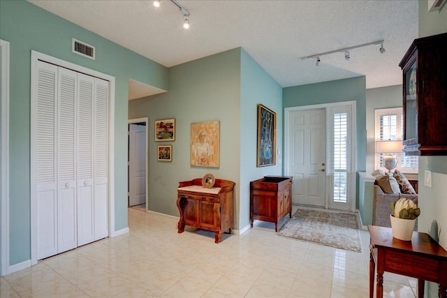 entrance foyer with rail lighting and a textured ceiling