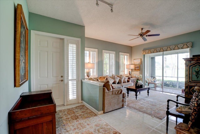 living room featuring ceiling fan, a textured ceiling, track lighting, and light tile patterned flooring