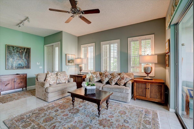 tiled living room with ceiling fan, rail lighting, and a textured ceiling