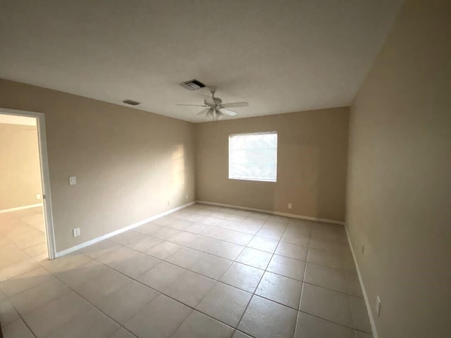 empty room with ceiling fan and light tile patterned floors