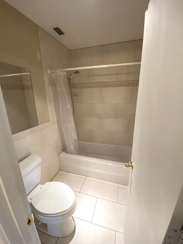 bathroom featuring toilet, tile patterned floors, tile walls, and shower / bath combo