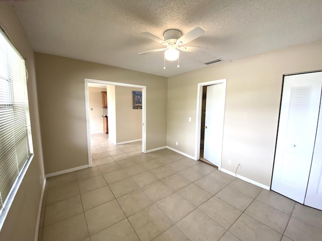 unfurnished bedroom with ceiling fan, light tile patterned flooring, and a textured ceiling