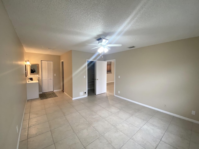 tiled spare room featuring a textured ceiling and ceiling fan