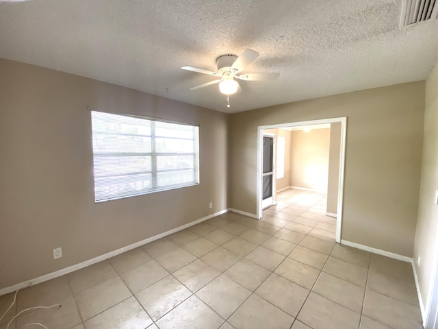 unfurnished room featuring ceiling fan, light tile patterned flooring, and a textured ceiling