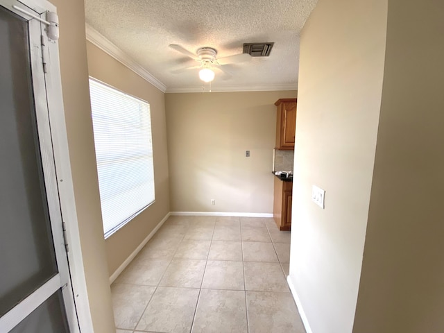 unfurnished dining area featuring a textured ceiling, ceiling fan, light tile patterned flooring, and crown molding