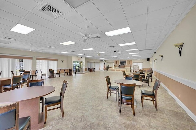 dining space with ceiling fan and a drop ceiling