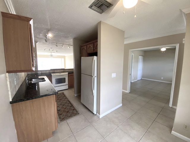 kitchen featuring tasteful backsplash, sink, light tile patterned floors, white appliances, and a textured ceiling