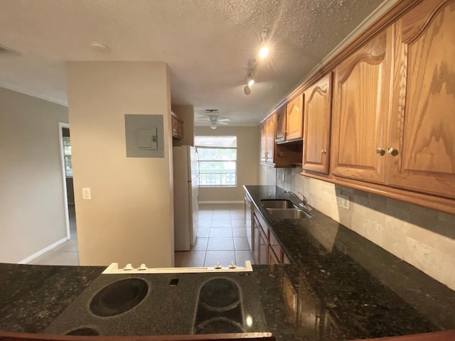 kitchen with dark stone countertops, white fridge, sink, a textured ceiling, and rail lighting