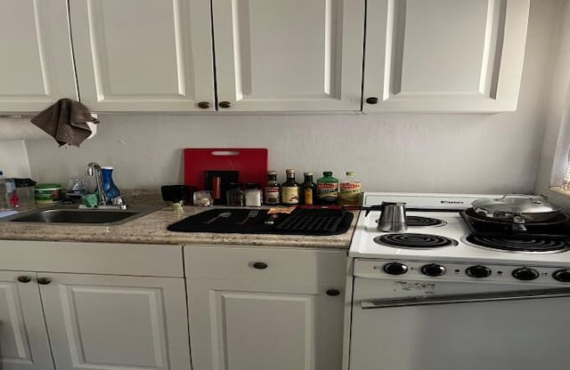 kitchen with electric stove, white cabinets, and sink