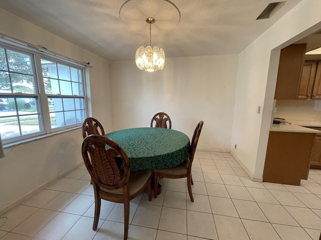 dining space with a textured ceiling, light tile patterned floors, and a notable chandelier