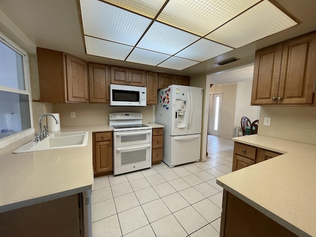 kitchen featuring sink, light tile patterned flooring, and white appliances