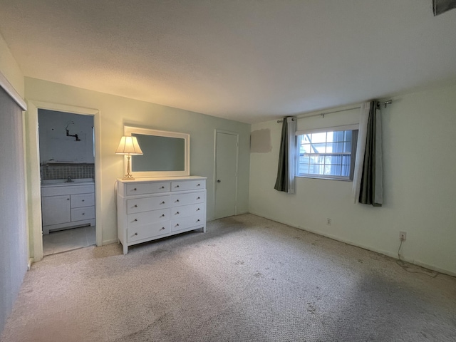 unfurnished bedroom featuring light carpet and ensuite bath