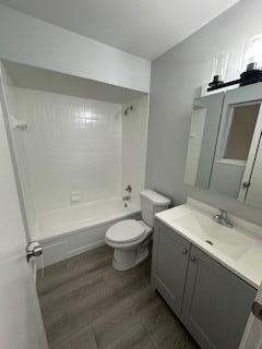 full bathroom with hardwood / wood-style flooring, toilet, vanity, and tiled shower / bath combo