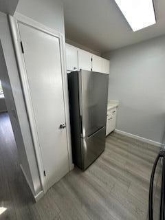 kitchen featuring stainless steel refrigerator, white cabinetry, and light hardwood / wood-style floors