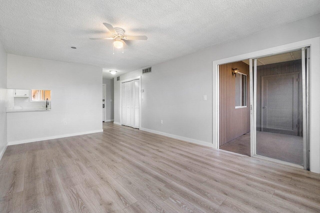 unfurnished living room featuring ceiling fan, a textured ceiling, and light wood-type flooring