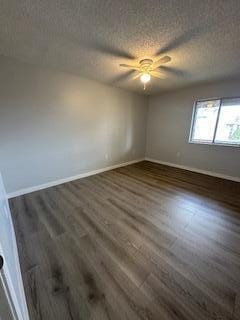 spare room with ceiling fan, a textured ceiling, and dark hardwood / wood-style flooring