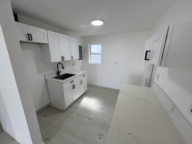 kitchen featuring sink, light stone counters, and white cabinetry