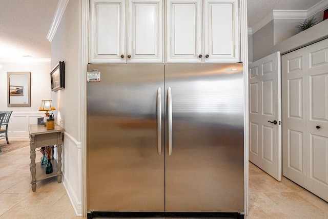 kitchen featuring ornamental molding, light tile patterned flooring, white cabinets, and stainless steel refrigerator