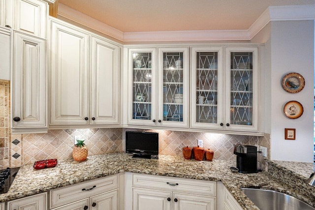 kitchen featuring sink, light stone counters, ornamental molding, decorative backsplash, and white cabinets