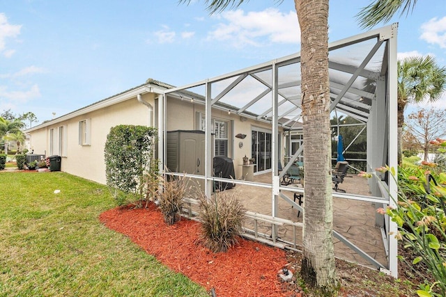 back of house featuring a lawn and glass enclosure