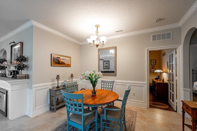 dining room with ornamental molding, light tile patterned floors, a notable chandelier, and a textured ceiling