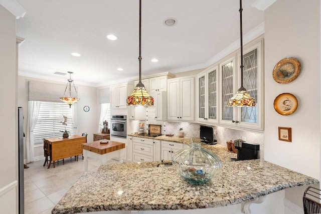 kitchen featuring decorative light fixtures, oven, backsplash, kitchen peninsula, and crown molding