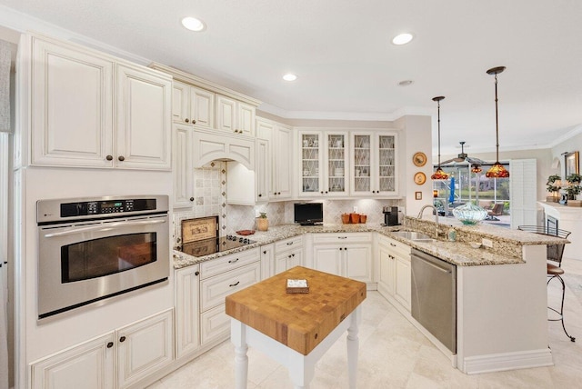 kitchen featuring pendant lighting, sink, a kitchen breakfast bar, kitchen peninsula, and stainless steel appliances