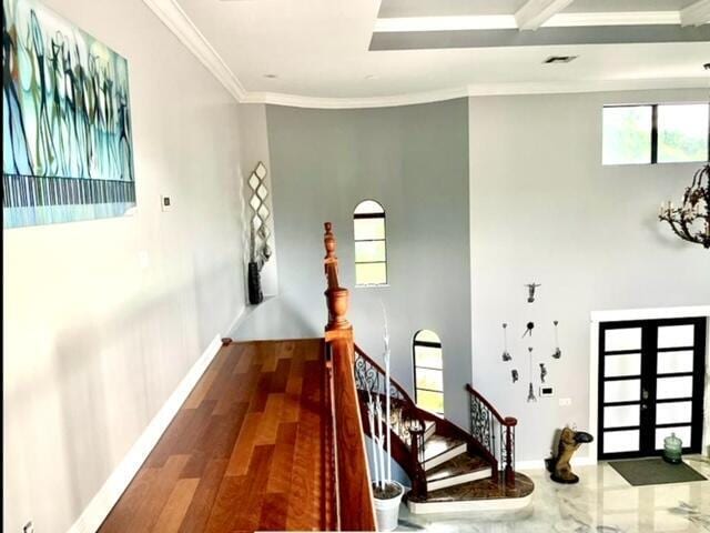 hall with hardwood / wood-style flooring, ornamental molding, and french doors