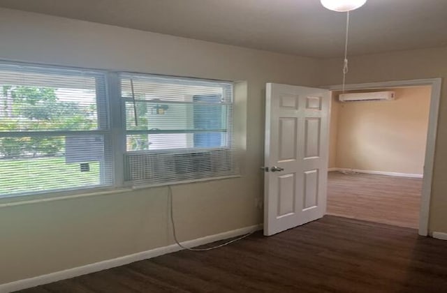 interior space with a wall unit AC and dark hardwood / wood-style flooring