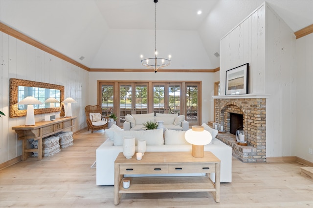 living area featuring light wood-style floors, a fireplace, high vaulted ceiling, and a chandelier