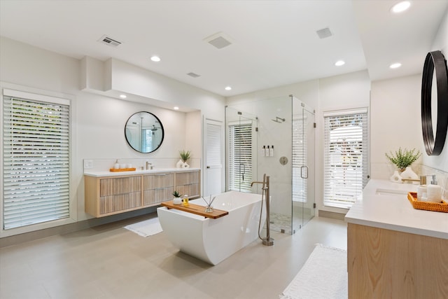 bathroom featuring recessed lighting, two vanities, visible vents, a shower stall, and a freestanding tub