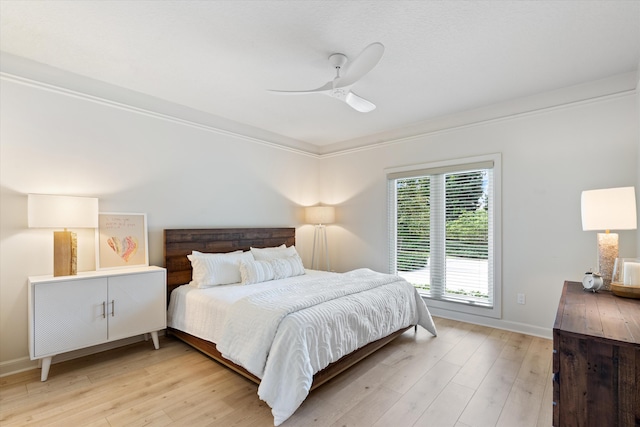 bedroom with light wood-style floors, crown molding, baseboards, and a ceiling fan