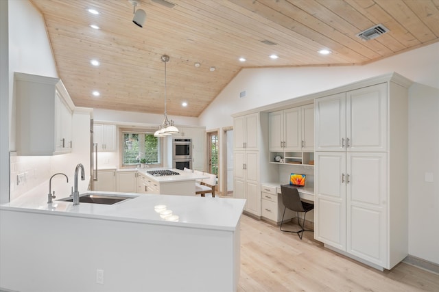 kitchen with light countertops, visible vents, decorative light fixtures, and built in desk