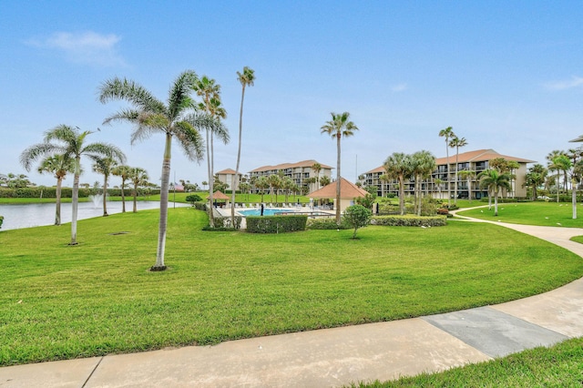 view of property's community with a water view and a lawn