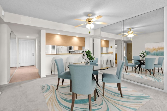 carpeted dining area with ceiling fan and a textured ceiling