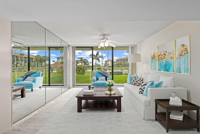 living room featuring ceiling fan, a textured ceiling, and a wall of windows