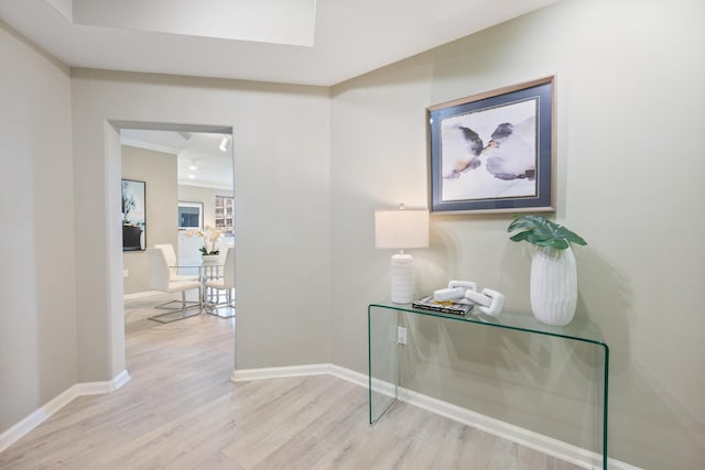 hall with ornamental molding and light hardwood / wood-style flooring