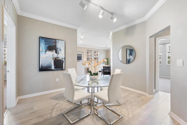 dining space featuring a textured ceiling, ornamental molding, and light hardwood / wood-style flooring