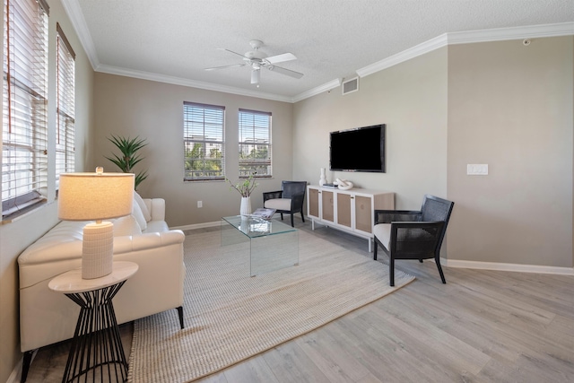 living room featuring ceiling fan, light wood-type flooring, crown molding, and a textured ceiling