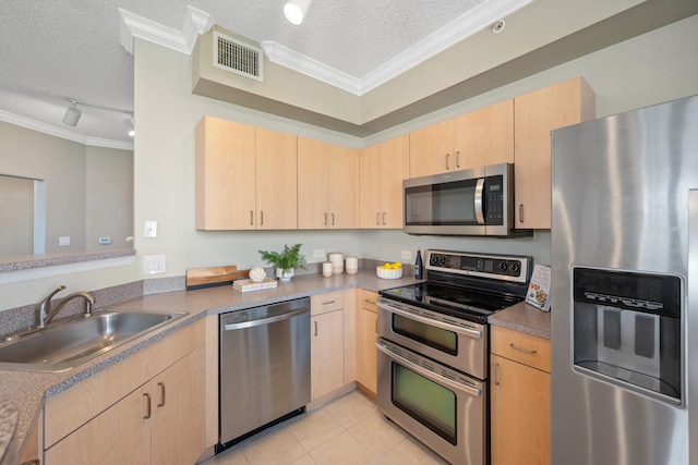 kitchen with sink, light brown cabinets, track lighting, stainless steel appliances, and a textured ceiling