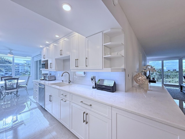 kitchen with white cabinets, sink, light stone counters, light tile patterned floors, and stainless steel dishwasher