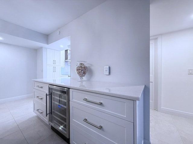 kitchen with white cabinetry, beverage cooler, and light stone counters