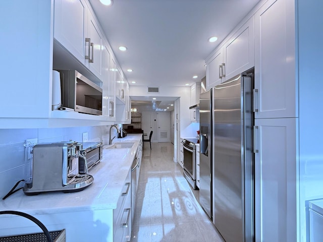 kitchen featuring light stone countertops, white cabinetry, appliances with stainless steel finishes, and sink